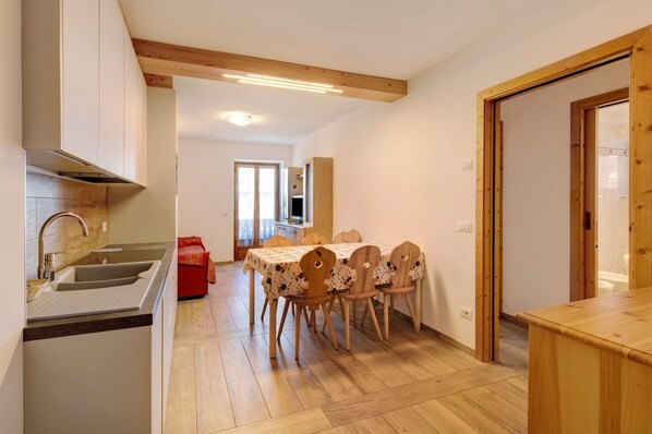 A kitchen with a sink, wooden cabinets, a dining table with chairs, and a red object on the floor.
