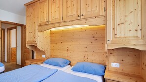 Une pièce aménagée comme un chalet en bois, avec deux lits, une armoire en bois et une petite table.