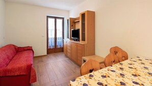 Une pièce comprenant un meuble en bois, une télévision, un canapé rouge et une couvre-lit à motifs.