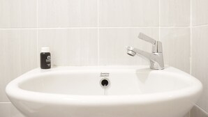 Un lavandino bianco con un solo rubinetto e una bottiglia di sapone per le mani.