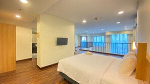Ein Hotelzimmer mit einem großen Bett, einem an der Wand befestigten Fernseher und einem Balkon mit Geländer.