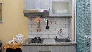 Une cuisine compacte équipée d’une cuisinière à gaz, d’un four encastré, d’une hotte en acier inoxydable et d’un petit évier.