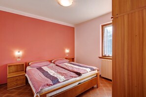 A bedroom with a bed, nightstands, a window, and a radiator.