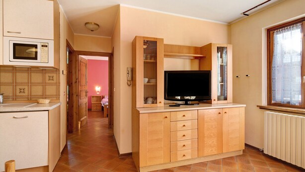 Eine kleine Küche mit Mikrowelle, Holzschränken, einem Fernseher und einem Fenster mit Blick.