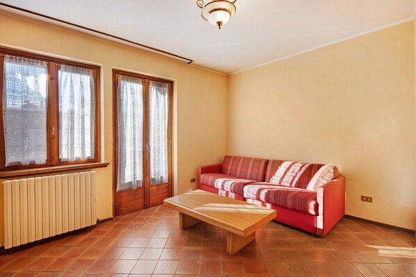 A living room with a red sofa, a wooden coffee table, and a radiator.