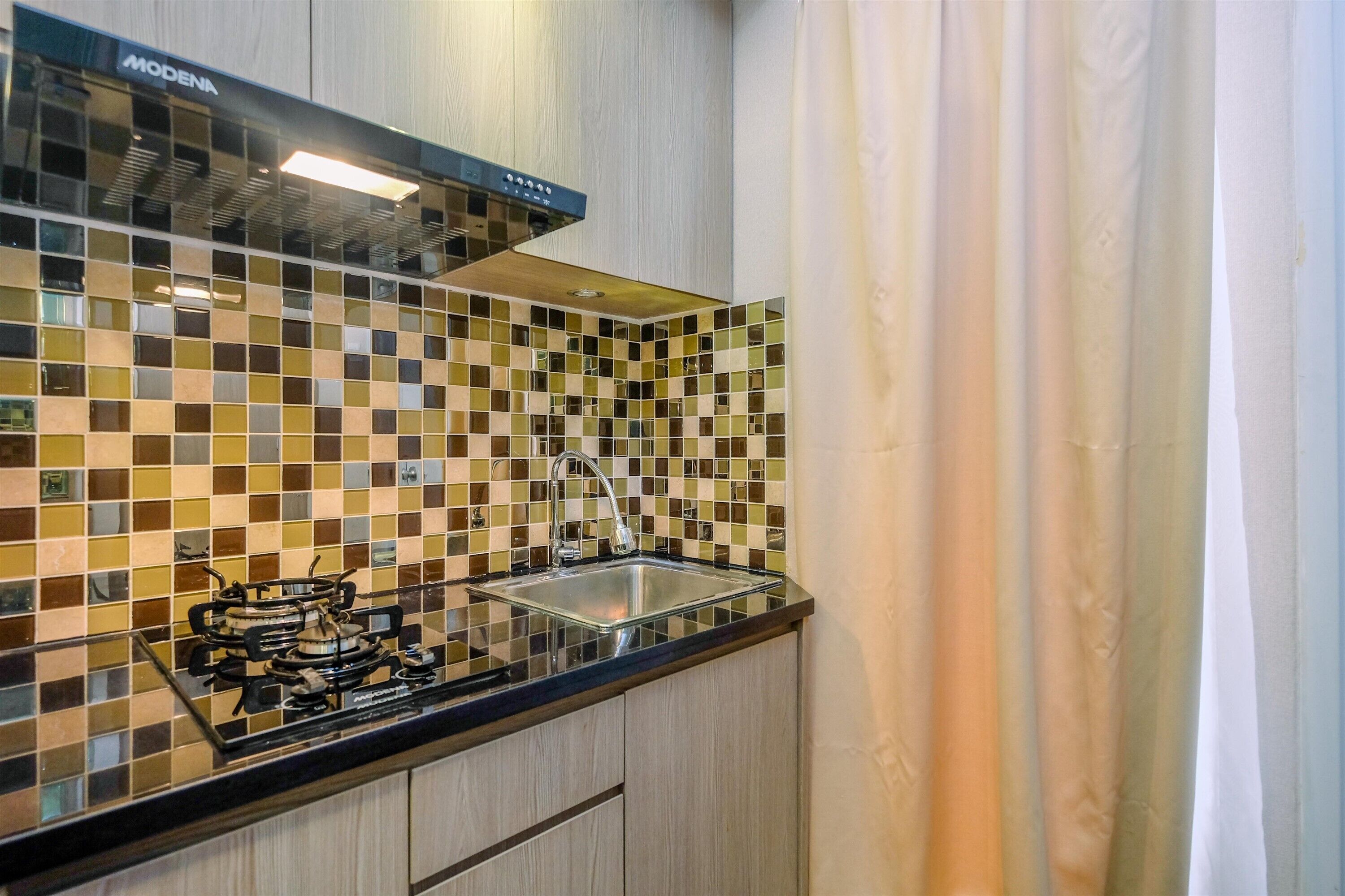 A kitchen with a black countertop, a gas stove, a sink, and a tiled backsplash.