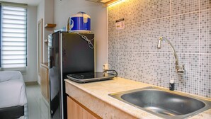 A compact kitchenette with a refrigerator, a microwave, a sink, and a tiled backsplash. - Nice And Cozy Studio At Evenciio Apartment (Depok)