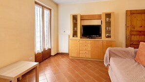 Ein Zimmer mit einem Bett, einem Fernseher, einem Holzschrank und einem Fenster.