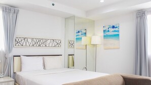 A hotel room with a bed, bedside lamps, a sofa, and artwork on the walls.