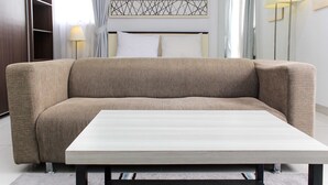 A modern bedroom with a sofa bed, a bedside table, and a wall-mounted artwork above the bed.