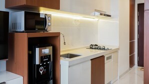 A modern kitchen with a built-in microwave, a water dispenser, and a gas stove. - Cozy Studio Sky House Apartment Near Aeon & Ice Bsd (Pagedangan)