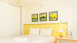 A hotel room with a bed, a nightstand, and three paintings on the wall. - Nice And Elegant 1Br Apartment At Mustika Golf Residence (Cikarang)