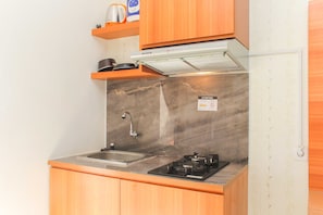 A compact kitchen with a gas stove, a sink, and wooden cabinets.