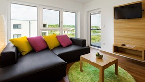 A modern living room with a sectional sofa, a coffee table, and a flat-screen TV mounted on the wall. - Heritage Apartment with Swimming Pond (Zsira)