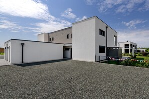 A modern two-story building with a flat roof and a gravel driveway.