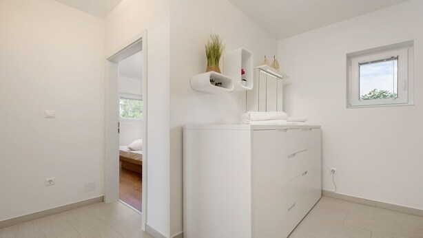 A modern bathroom with a white vanity, a mirror, and a small window. - Heritage Apartment with Swimming Pond (Zsira)