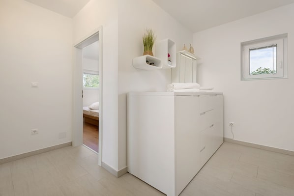 Une salle de bain moderne avec un meuble-lavabo blanc, un miroir et une petite fenêtre.