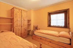 Une chambre avec deux lits, une armoire en bois et une fenêtre avec des rideaux.