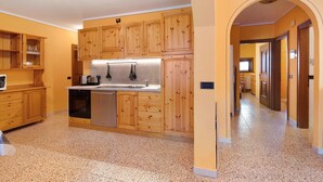 Une cuisine avec des meubles en bois, un réfrigérateur en acier inoxydable et un four encastré.