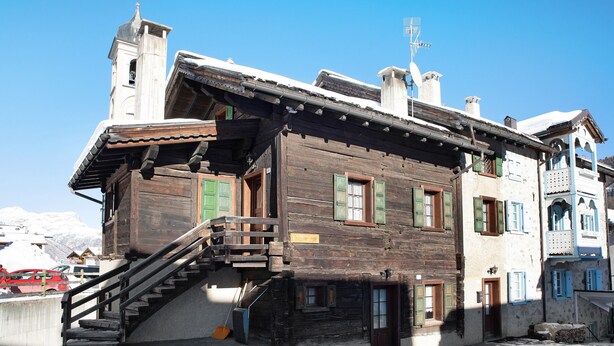Un bâtiment en bois doté d’un escalier, d’un balcon et d’un clocher.