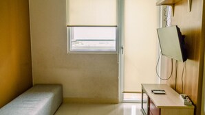 Una habitación pequeña con una cama individual, un escritorio con televisor y una ventana con vistas.