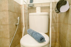 A bathroom with a toilet, a towel, and a shower head. - Comfort And Simple 2Br At Green Pramuka City Apartment (Jakarta)