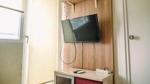 Un televisor montado en una pared de madera con un estante encima.