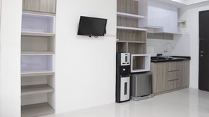 A modern kitchen with built-in appliances, white cabinetry, and a flat-screen TV. - Spacious And Modern Studio Room Apartment At Grand Asia Afrika (Bandung)