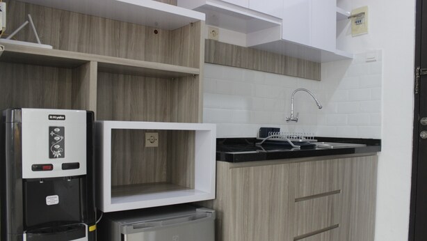 A modern kitchen with built-in appliances, a microwave, and a sink. - Spacious And Modern Studio Room Apartment At Grand Asia Afrika (Bandung)