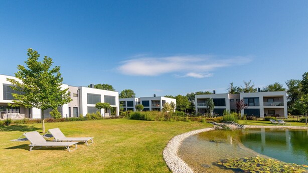 A modern residential complex with multiple two-story buildings, a grassy lawn, and a small pond with lily pads. - Apartment in Zsira near Thermal Spa (Zsira)