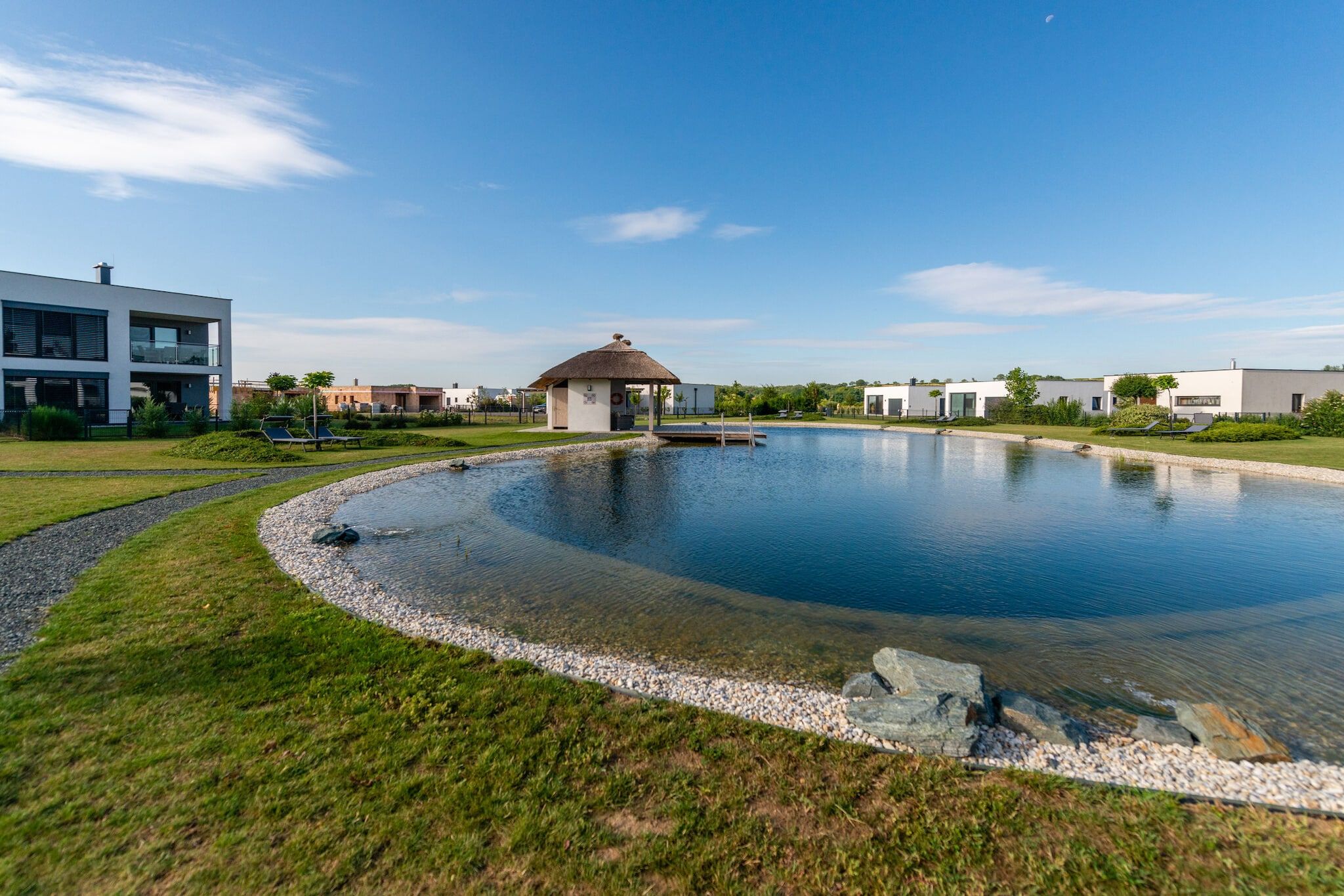 A modern building with a swimming pool, surrounded by a well-maintained lawn and a clear sky.