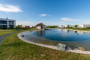 A modern building with a swimming pool, surrounded by a well-maintained lawn and a clear sky.