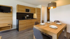 A modern kitchen with wooden cabinets, a built-in microwave, and a dining area with a table set for four. - Apartment in Zsira near Thermal Spa (Zsira)