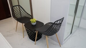 A small table with two chairs and a potted plant. - Elegant And Comfortable Studio Sky House Bsd Apartment (Pagedangan)