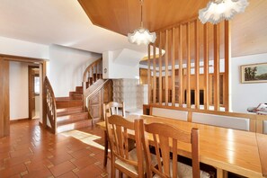 Ein Holzespeisesaal mit Stühlen, einer Treppe und einer dekorativen Deckenleuchte.