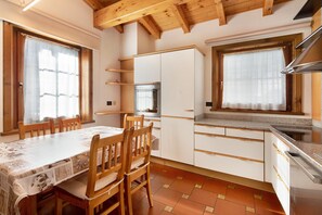 Une cuisine avec des chaises en bois, une table et un fourneau.