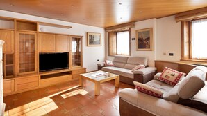 Ein Wohnzimmer mit Flachbildfernseher, Holzschränken, einer Couch und einem Couchtisch.