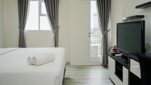 A hotel room with a bed, a TV, and a window with curtains. - Elegant Studio At Bintaro Icon Apartment Near Bintaro Xchange Mall (South Tangerang)