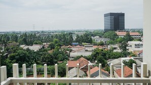 A view of a cityscape with a prominent modern building, residential houses, and greenery. - Elegant Studio At Bintaro Icon Apartment Near Bintaro Xchange Mall (South Tangerang)