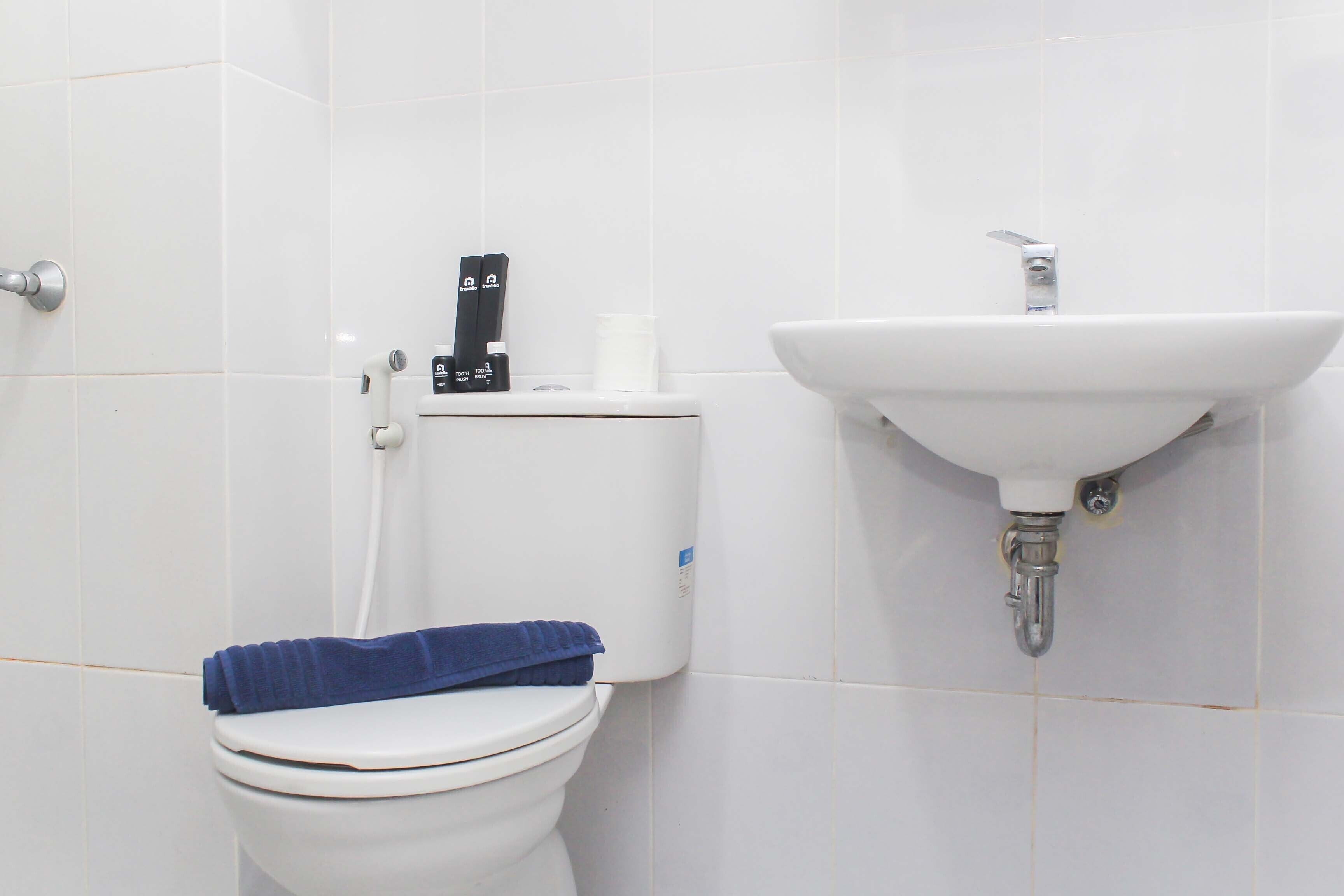Une salle de bain équipée de toilettes, d’un lavabo et d’un porte-rouleau de papier toilette.