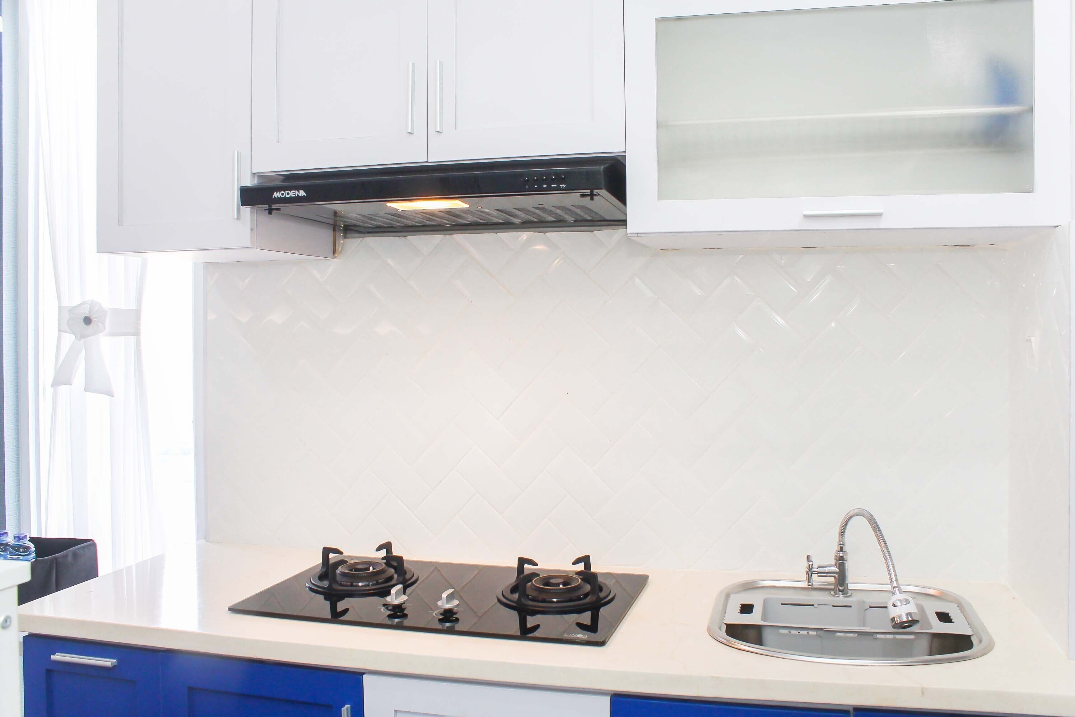 A kitchen with white cabinets, a gas stove, a sink, and a window above the stove.