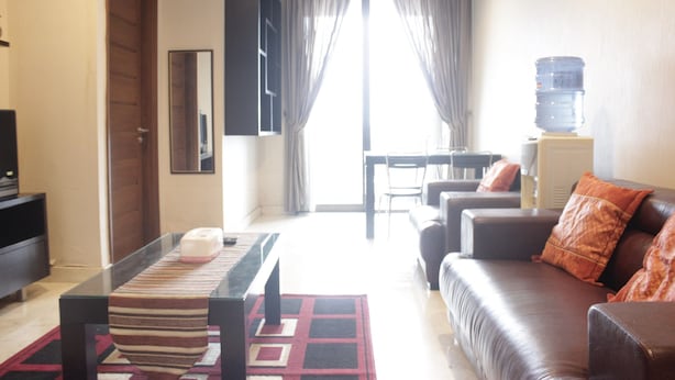A living room with a sofa, a coffee table, a TV, and a water dispenser. - Deluxe 2Br At Dago Boutique Apartment (Bandung)