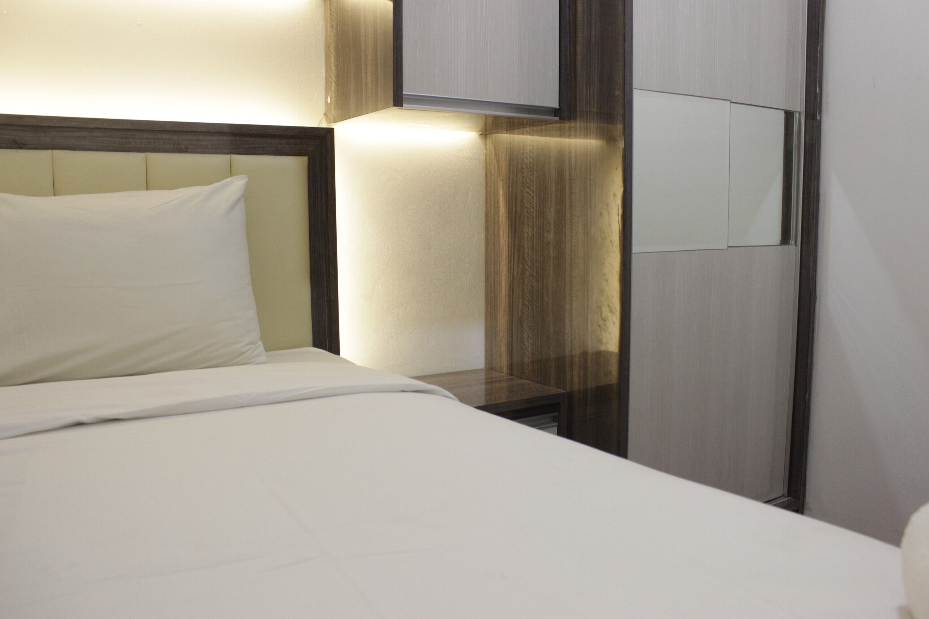 A hotel room with a neatly made bed, a bedside table, and a wall-mounted TV.