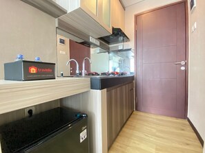 A compact kitchen with a built-in oven, a sink, and a compact refrigerator.