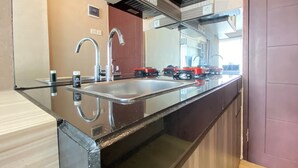 A modern kitchen with a stainless steel sink, a double faucet, and a built-in oven. - Modern And Cozy Studio Room At Gateway Pasteur Apartment (Cimahi)