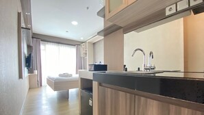 A modern kitchen with a wooden countertop, a sink, and a built-in oven. - Modern And Cozy Studio Room At Gateway Pasteur Apartment (Cimahi)