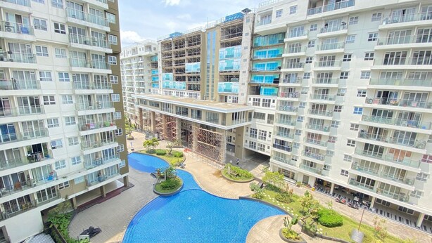 A high-rise residential building with multiple balconies, a central courtyard with a swimming pool, and surrounding greenery. - Modern And Cozy Studio Room At Gateway Pasteur Apartment (Cimahi)