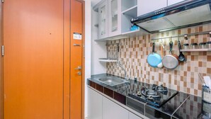 A kitchen with a black countertop, stainless steel sink, and a range hood. There are cabinets above the counter and a tiled backsplash. - Warm And Cozy Studio Apartment Margonda Residence 5 Near Campus (Depok)