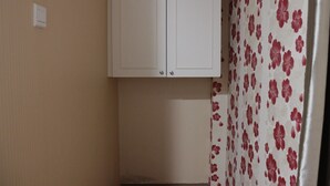 Une pièce avec une armoire blanche, un mur beige et un rideau à motifs floraux.