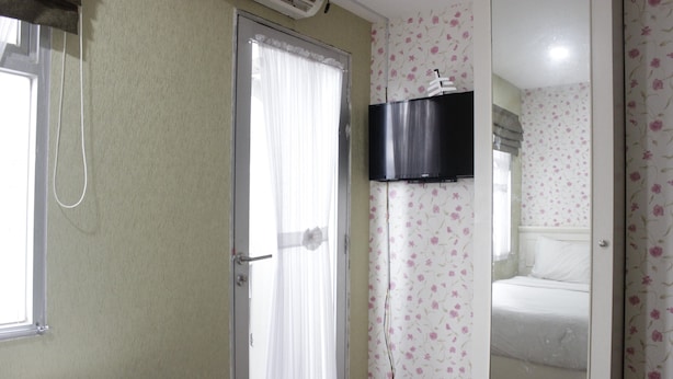 Une chambre d’hôtel équipée d’un lit, d’un téléviseur fixé au mur et d’un espace douche.